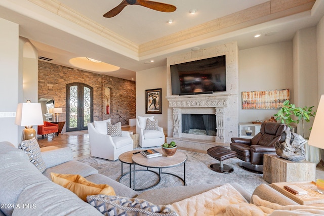 living room featuring ceiling fan, a raised ceiling, crown molding, and a high end fireplace