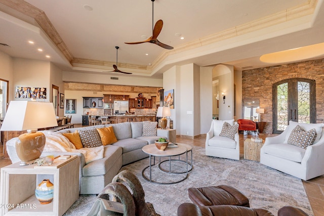 living room featuring a raised ceiling, crown molding, ceiling fan, and french doors