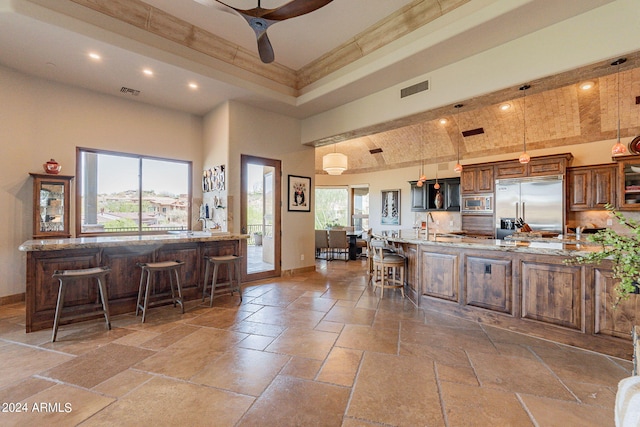 kitchen with hanging light fixtures, plenty of natural light, built in appliances, and a breakfast bar area