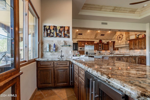 kitchen with beverage cooler, backsplash, a raised ceiling, and appliances with stainless steel finishes