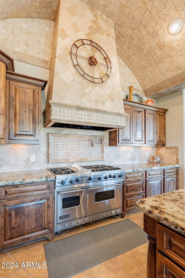 kitchen featuring vaulted ceiling, decorative backsplash, double oven range, light stone countertops, and brick ceiling