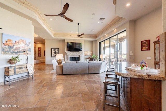 living room featuring ornamental molding, a tray ceiling, and ceiling fan