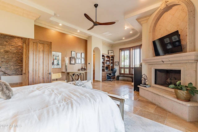 bedroom featuring ornamental molding, a large fireplace, and ceiling fan