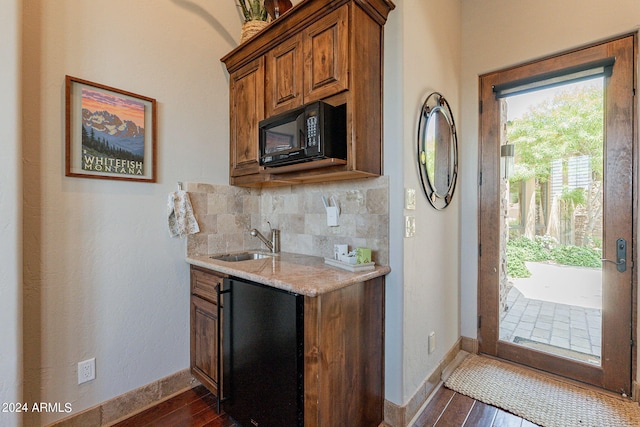 kitchen with light stone counters, tasteful backsplash, sink, black appliances, and dark hardwood / wood-style flooring