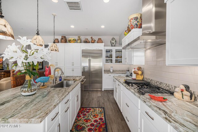 kitchen featuring pendant lighting, an island with sink, white cabinets, wall chimney range hood, and dark hardwood / wood-style floors