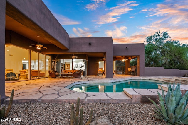 pool at dusk with a patio and ceiling fan