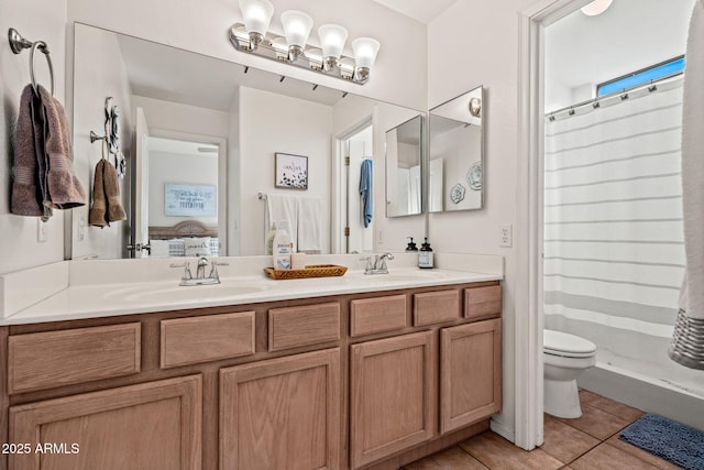 ensuite bathroom featuring toilet, ensuite bath, a sink, and tile patterned floors