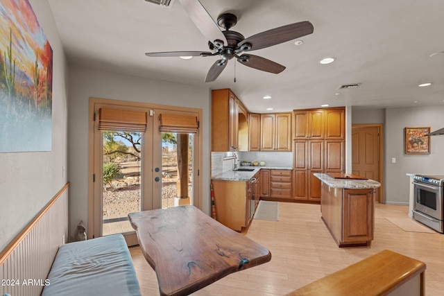 kitchen with ceiling fan, stainless steel electric stove, sink, light hardwood / wood-style flooring, and a center island