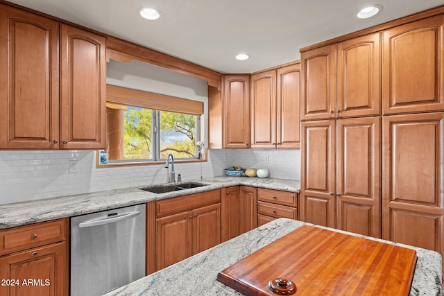 kitchen with light stone counters, tasteful backsplash, stainless steel dishwasher, and sink