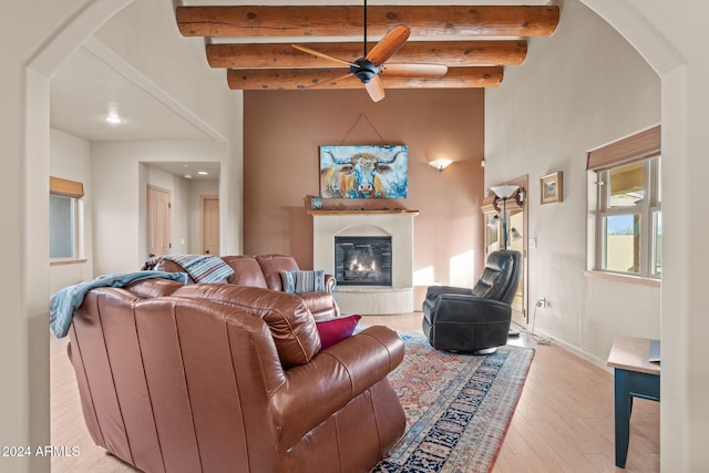 living room with beamed ceiling, light wood-type flooring, and ceiling fan