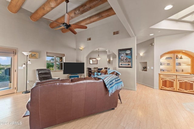 living room with beam ceiling, a towering ceiling, light hardwood / wood-style floors, and ceiling fan