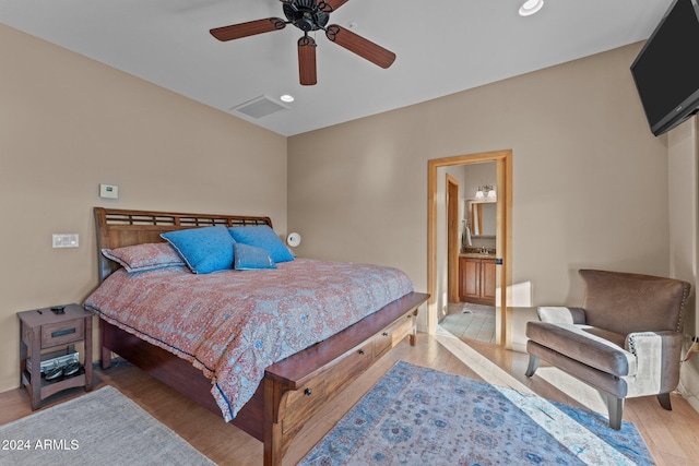 bedroom featuring ensuite bathroom, ceiling fan, and light wood-type flooring