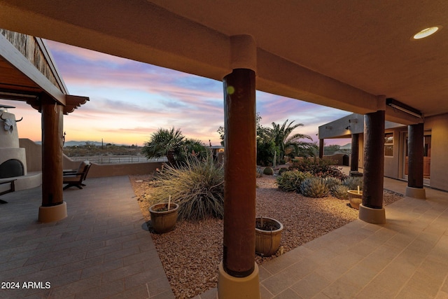 patio terrace at dusk featuring an outdoor fireplace