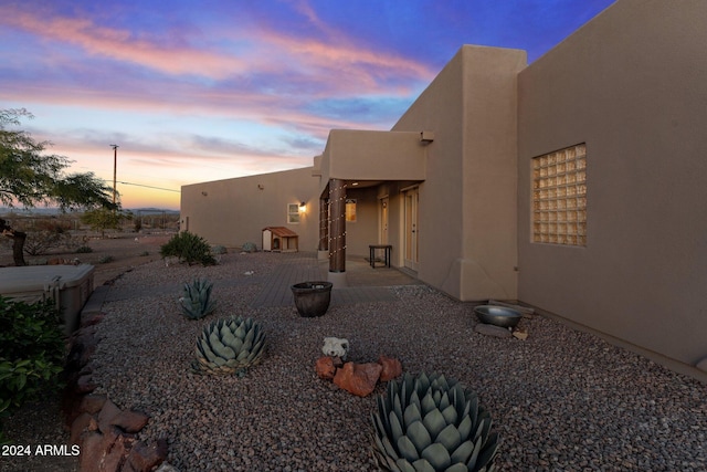 back house at dusk featuring a patio area