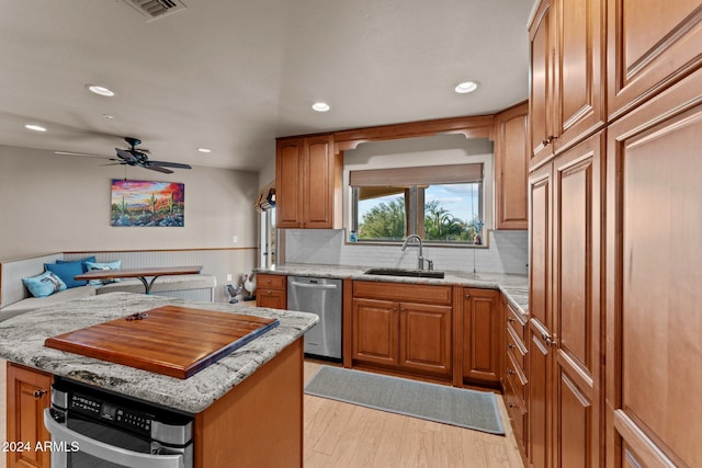 kitchen featuring sink, ceiling fan, light stone countertops, light hardwood / wood-style floors, and stainless steel appliances