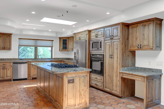 kitchen with a skylight, a kitchen island, light stone countertops, black appliances, and light tile patterned flooring