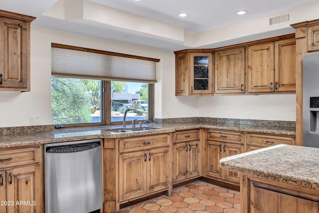 kitchen featuring light stone counters, sink, stainless steel dishwasher, and light tile patterned flooring