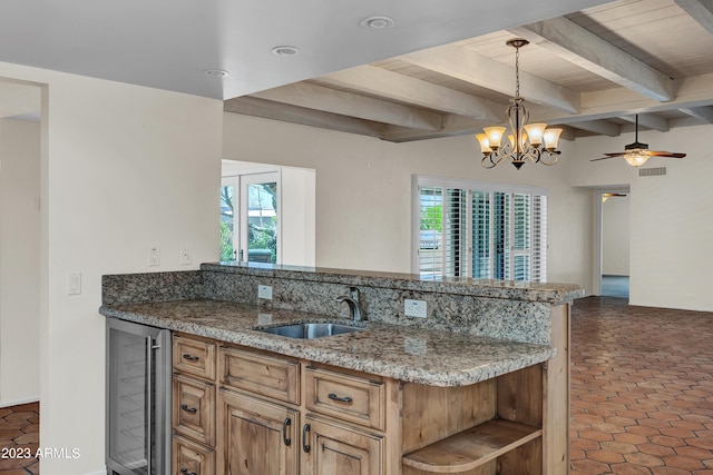 kitchen with a healthy amount of sunlight, light stone countertops, sink, and wine cooler