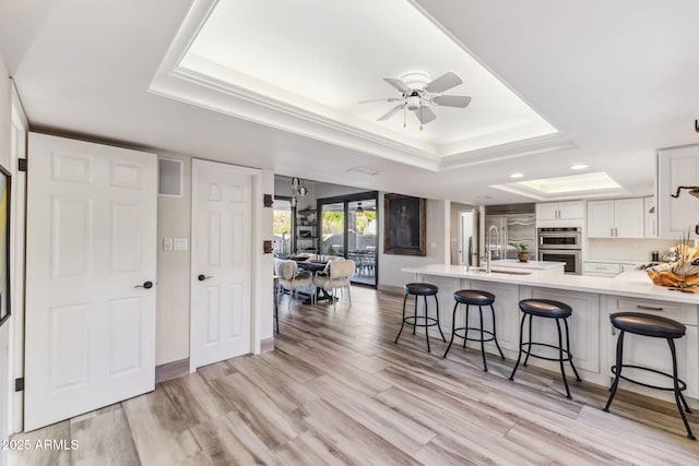 kitchen featuring a tray ceiling, a breakfast bar area, and white cabinets