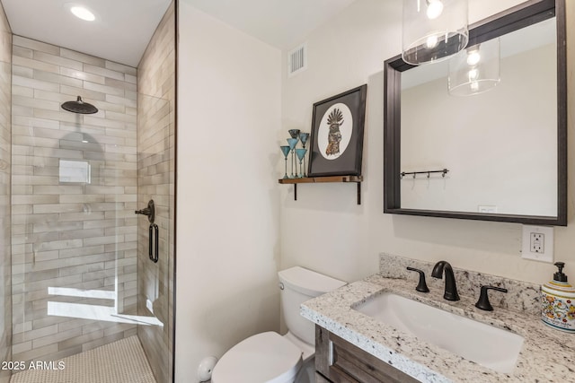 bathroom featuring a shower with door, vanity, and toilet