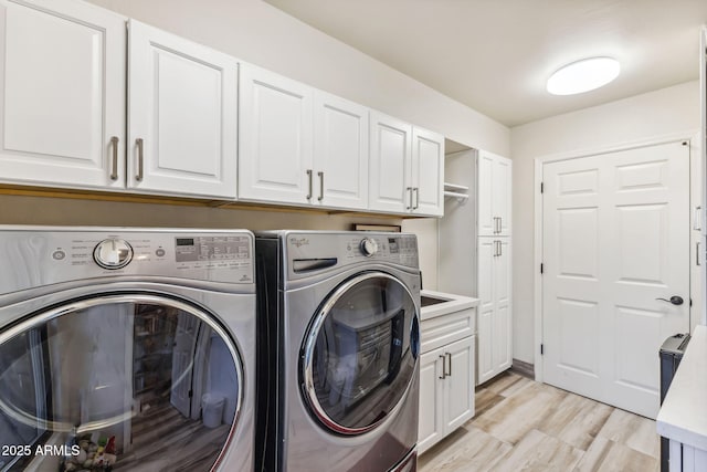 washroom with washer and clothes dryer, light hardwood / wood-style floors, and cabinets