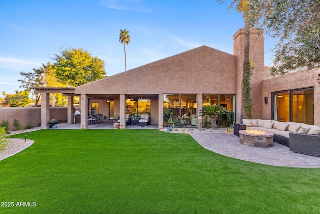 back of property with a lawn, an outdoor living space with a fire pit, and a patio area