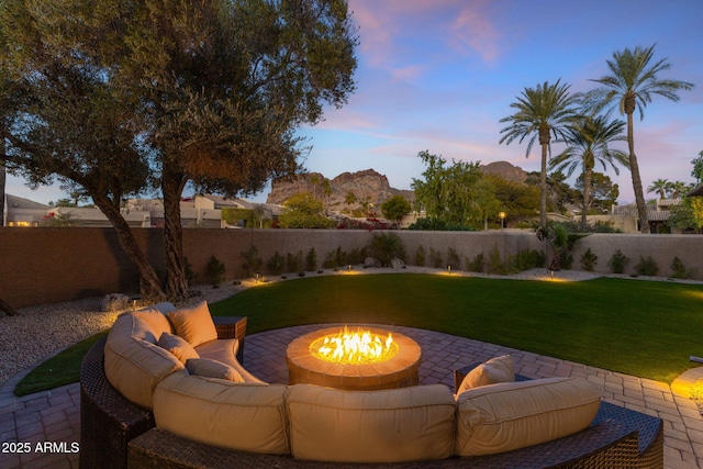 patio terrace at dusk with a mountain view, a yard, and an outdoor fire pit