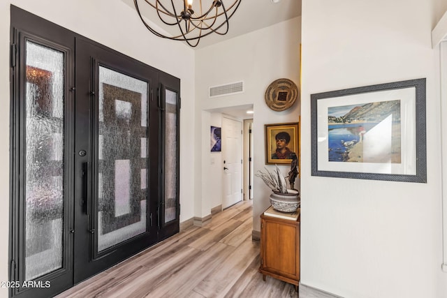 foyer entrance with a notable chandelier and light wood-type flooring