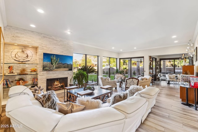 living room with ornamental molding, a stone fireplace, a wealth of natural light, and light wood-type flooring