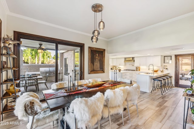 dining area featuring ornamental molding, sink, and light hardwood / wood-style floors