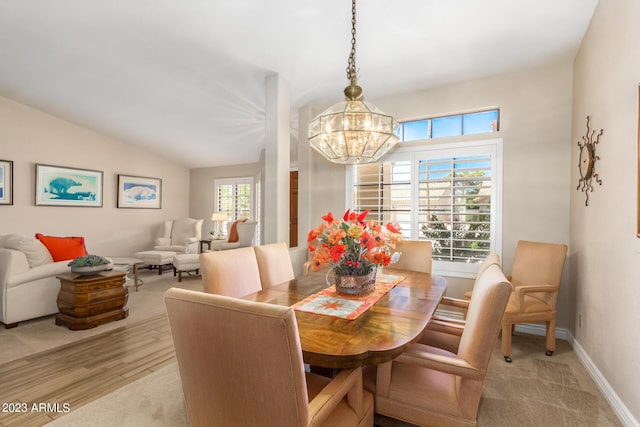 dining room with vaulted ceiling, an inviting chandelier, and light hardwood / wood-style flooring