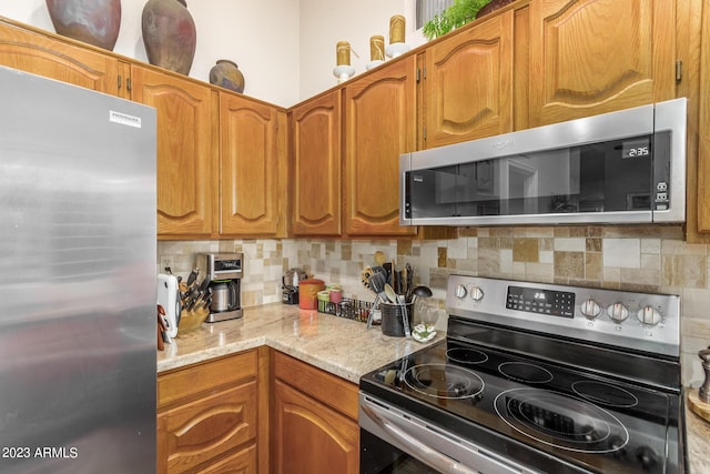 kitchen featuring stainless steel appliances, light stone countertops, and decorative backsplash