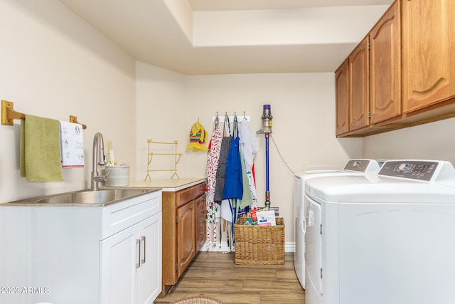 laundry room featuring sink, light hardwood / wood-style flooring, cabinets, and independent washer and dryer