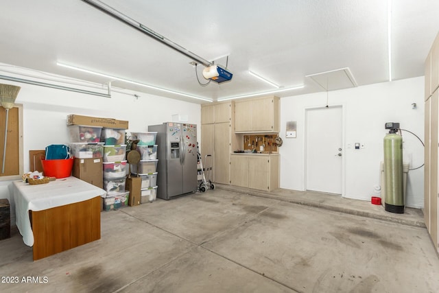 garage featuring a garage door opener and stainless steel fridge with ice dispenser