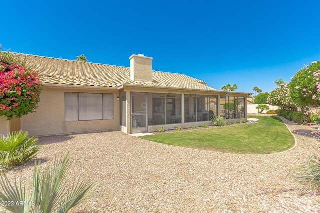 back of property with a sunroom and a lawn