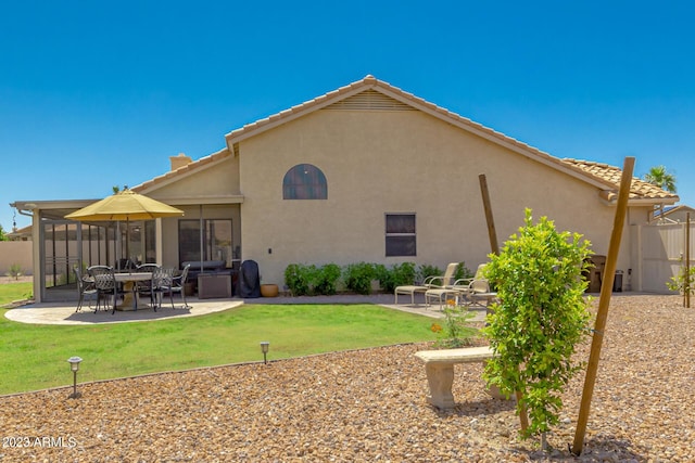 rear view of property with a yard, a patio area, and a sunroom