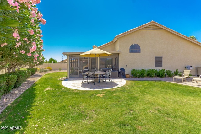 rear view of property featuring a patio, a sunroom, and a lawn