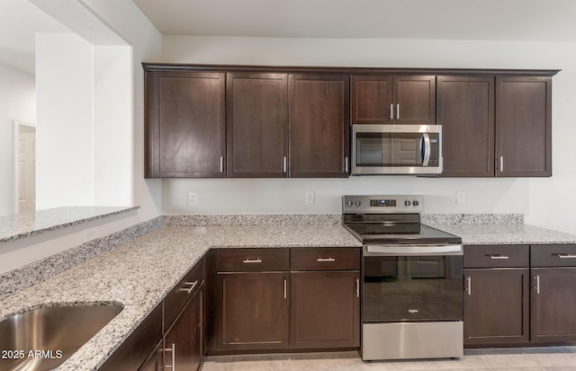 kitchen with dark brown cabinets, stainless steel appliances, and light stone counters