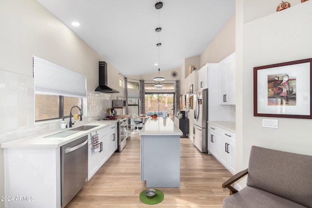 kitchen with tasteful backsplash, wall chimney exhaust hood, stainless steel appliances, a center island, and hanging light fixtures