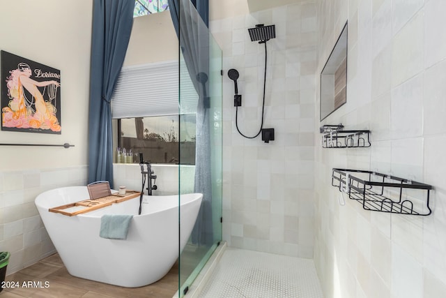 bathroom featuring plus walk in shower, tile patterned floors, a wealth of natural light, and tile walls