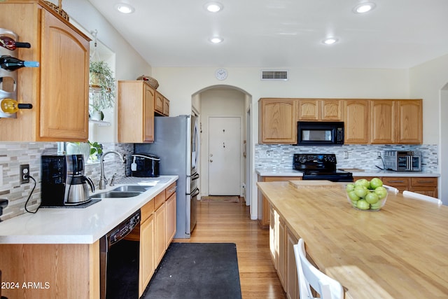 kitchen with light hardwood / wood-style floors, black appliances, sink, and backsplash