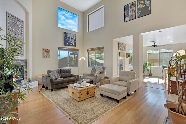 living room with a high ceiling, light wood-type flooring, and ceiling fan