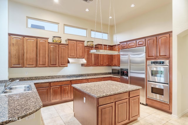 kitchen with light tile patterned flooring, a high ceiling, sink, appliances with stainless steel finishes, and a kitchen island