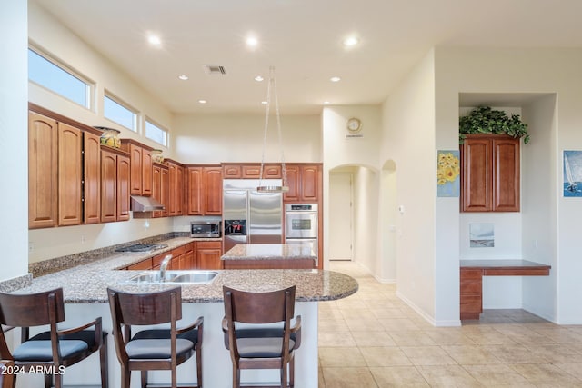 kitchen featuring sink, kitchen peninsula, a breakfast bar, light tile patterned flooring, and appliances with stainless steel finishes