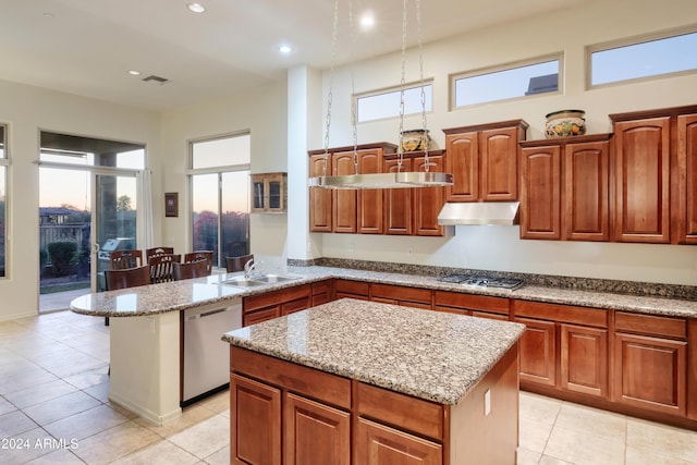 kitchen featuring stainless steel appliances, sink, light tile patterned floors, a center island, and a breakfast bar area