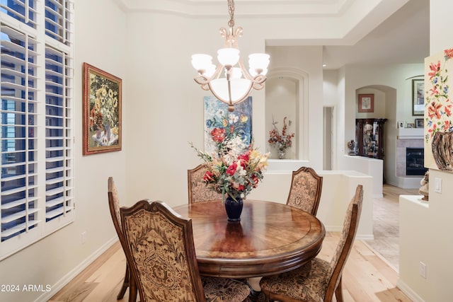 dining space with a fireplace, a chandelier, and light hardwood / wood-style floors