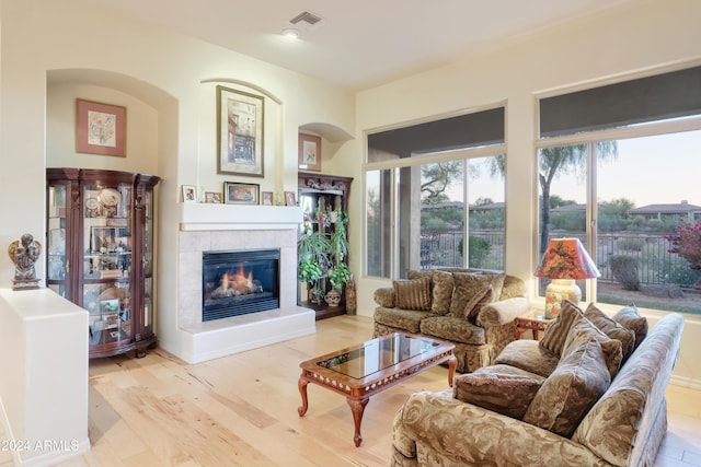 living room featuring a tiled fireplace and light hardwood / wood-style floors