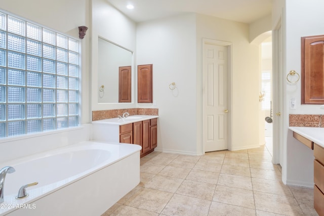 bathroom featuring tile patterned flooring, vanity, plenty of natural light, and a washtub