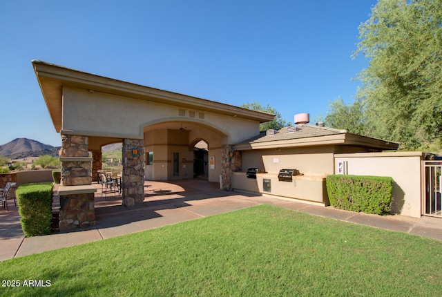 rear view of property with a mountain view, a yard, a patio, and area for grilling