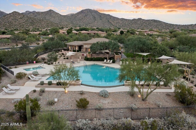 pool at dusk featuring a mountain view and a patio